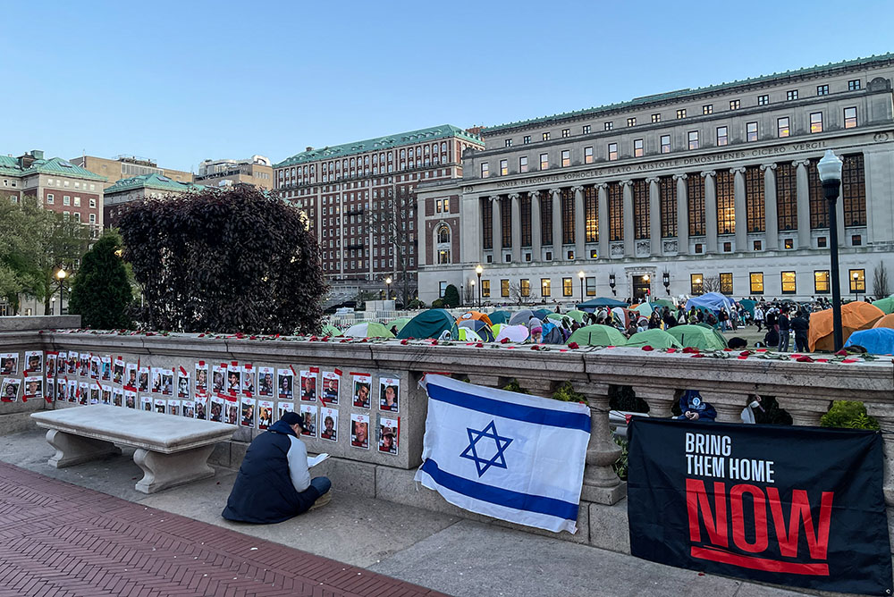 A Jewish student prays in front of pictures of Israeli hostages in Gaza, behind the pro-Palestinian student encampment on the campus of Columbia University in New York City on April 24. (NCR photo/Camillo Barone)