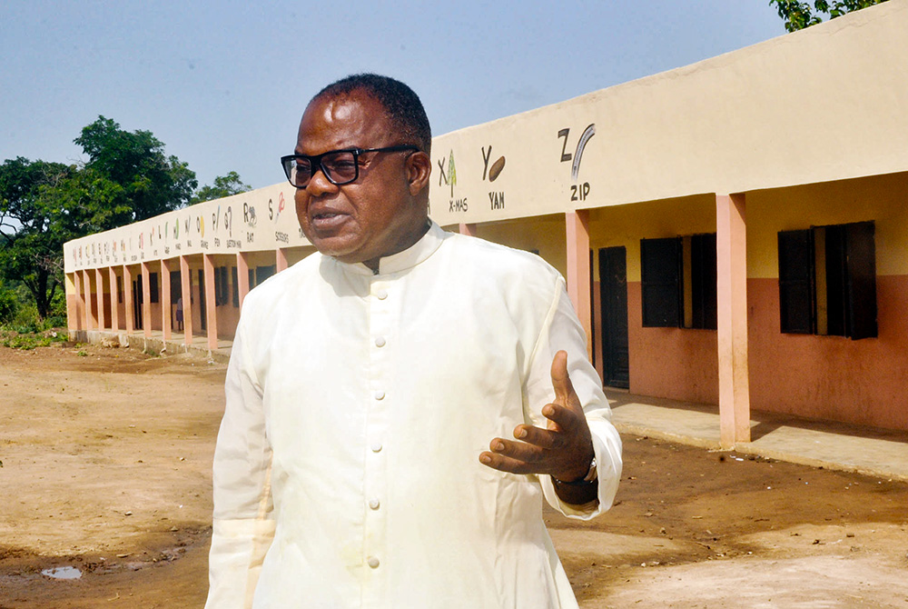 Fr. Peter Abue, a Nigerian Catholic priest offering free education and empowerment to families in marginalized communities through the CORAfrica initiative, poses for a photo in front of John Bosco Academy, which he founded in 2020 in Ogoja, Nigeria. (Valentine Benjamin)