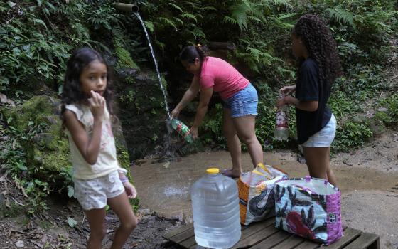 Young girl and family gather water from stream