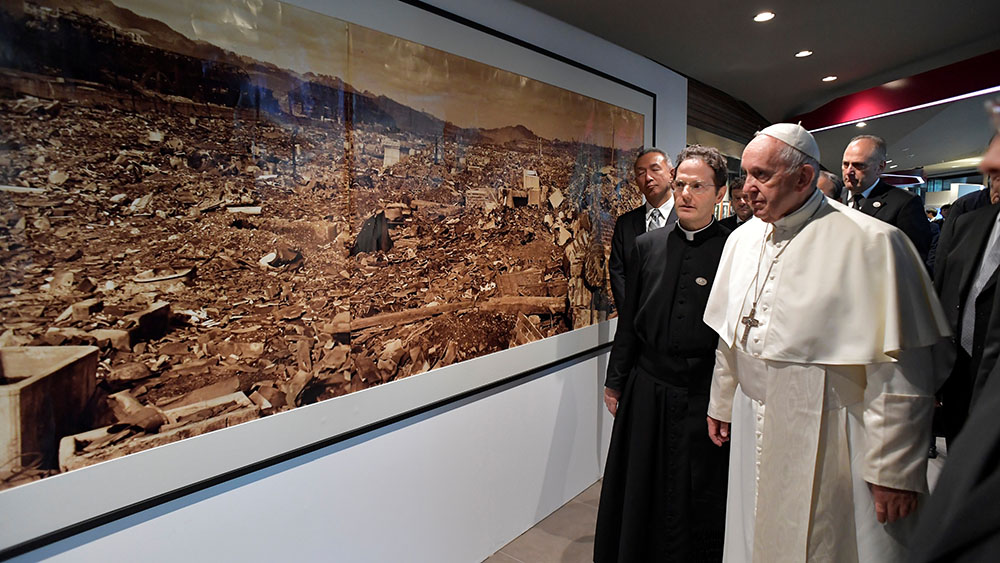 Pope Francis walks by a photo showing the destruction of an atomic bomb during a visit to the Jesuit-run Sophia University in Tokyo Nov. 26, 2019. (CNS/Vatican Media via Reuters)