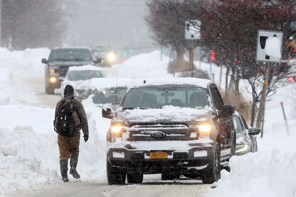 A man walks on the street as cars pass by in Amherst, N.Y., Dec. 26, 2022, during a deadly winter storm that hit the Buffalo region. (CNS/Reuters/Brendan McDermid)