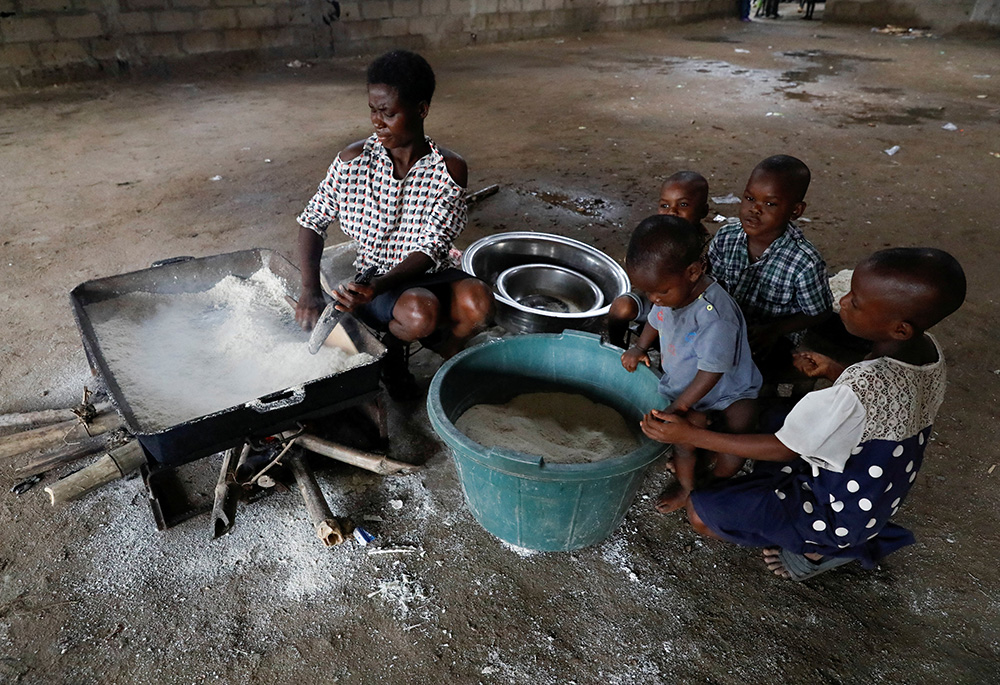 A woman displaced by flooding cooks food for her family at a school converted to relief camp Oct. 21, 2022, in Ogbogu, Nigeria. (CNS/Reuters/Temilade Adelaja)