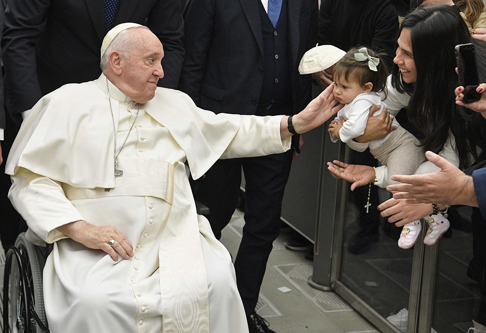 Pope Francis greets a baby during his general audience Jan. 25 at the Vatican. (CNS/Vatican Media)