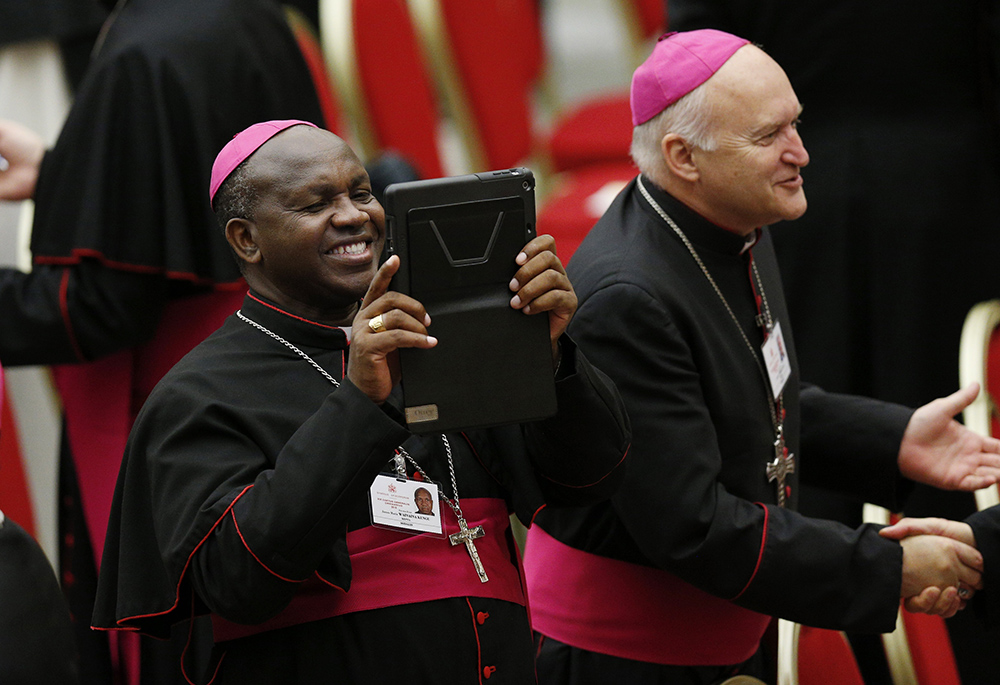 Bishop James Wainaina of Murang'a, Kenya, captures images on his tablet during a break at an event marking the 50th anniversary of the Synod of Bishops in the Paul VI hall at the Vatican Oct. 17, 2015. (CNS/Paul Haring)