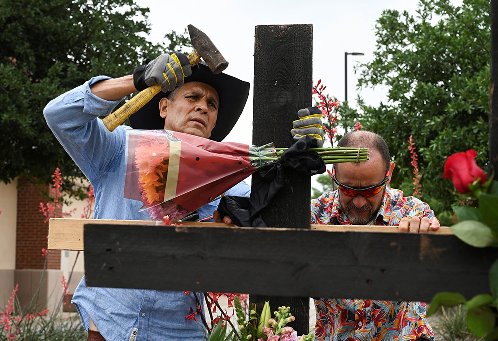 Muralist Roberto Marquez, left, and his friend Israel Gil from Dallas erect a memorial May 7 to honor the eight people killed the day before by a gunman at the Dallas-area Allen Premium Outlets mall in Allen, Texas. "This is like a refuge for the people who lost loved ones, a place where they can come and express all their emotions," said Marquez, who believes the memorial was a priority because people need a place to gather at such a difficult time. (OSV News/Reuters/Jeremy Lock)