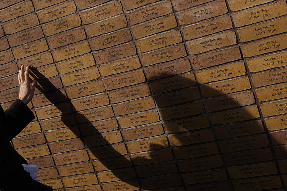 A woman touches the name stones of Holocaust victims of the Zilversmit family after the unveiling of a new monument in the heart of Amsterdam's historic Jewish Quarter on Sept. 19, 2021, honoring the 102,000 Dutch victims of the Holocaust. (AP/Peter Dejong)
