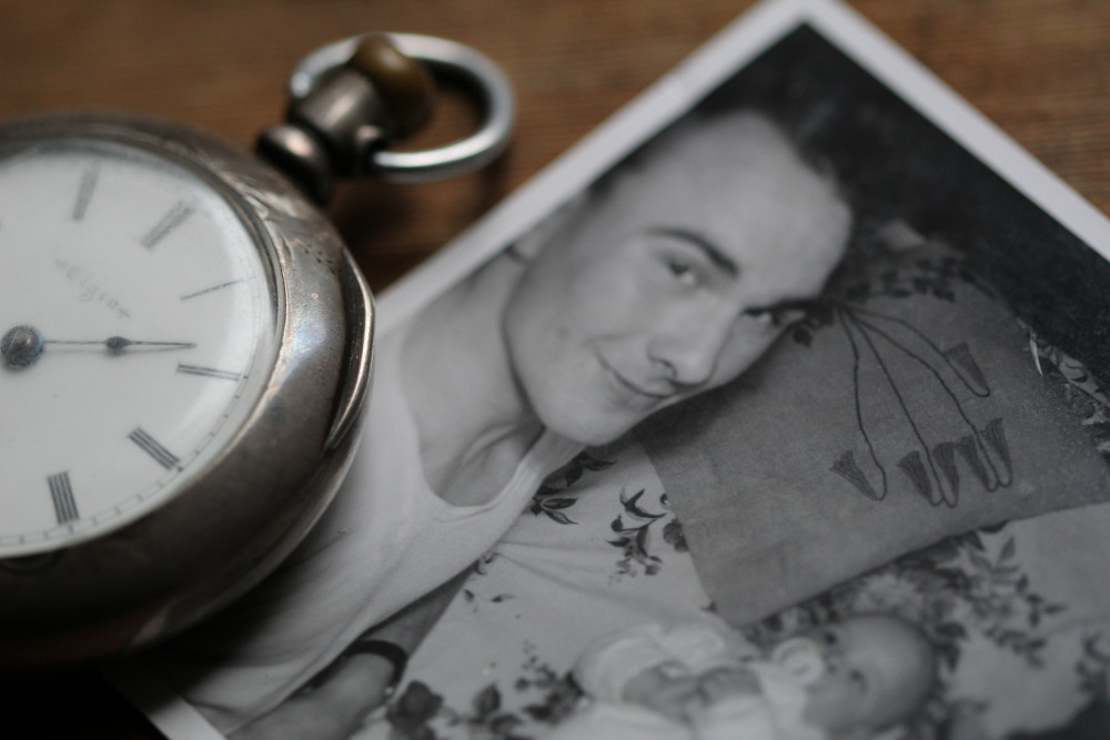 A black and white photograph of a father with his child next to a watch (Unsplash/Anne Nygard)
