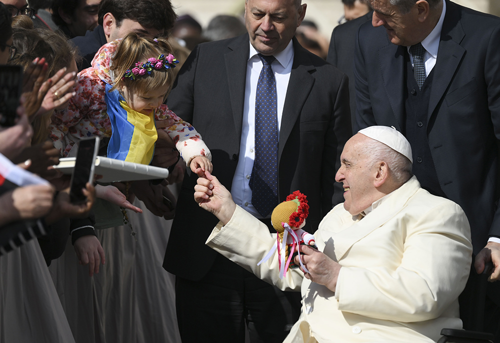 Pope Francis thanks a Ukrainian girl for the gift of a doll after his weekly general audience in St. Peter's Square April 5 at the Vatican. During the audience, praying for peace in Ukraine, the pope asked people to remember the Ukrainian and Russian mothers who have lost children in the war. (CNS/Vatican Media)