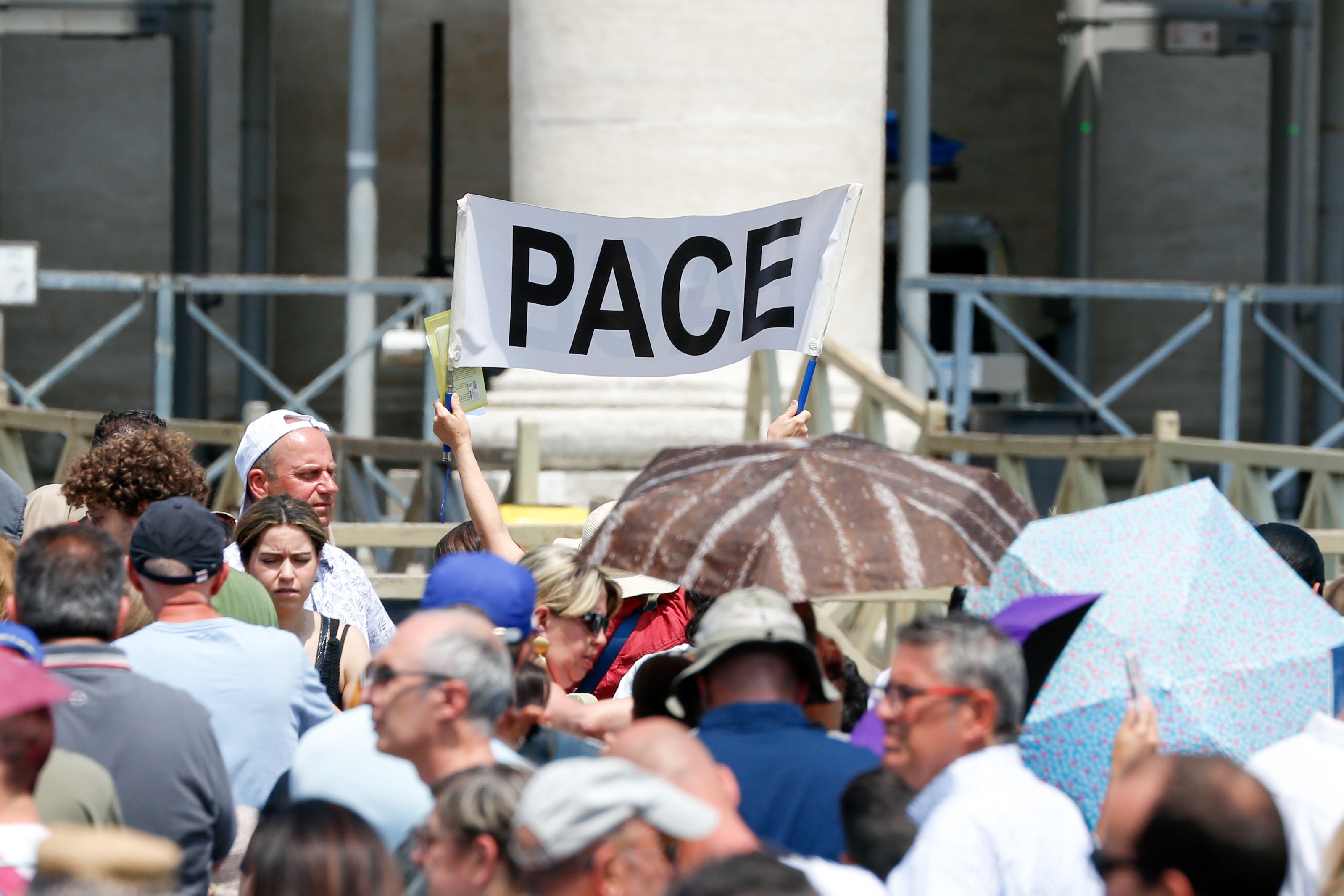 A person holds up a banner that reads "Pace" — "peace" — as visitors gather in St. Peter's Square at the Vatican to pray the Angelus with Pope Francis June 18. (CNS/Lola Gomez)