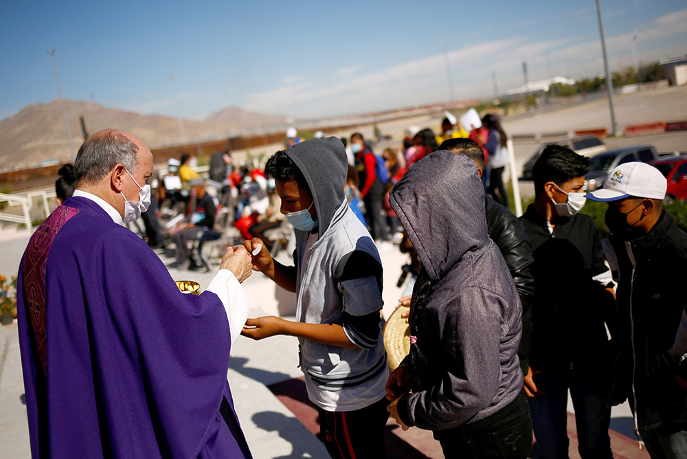 Bishop José Guadalupe Torres Campos of Ciudad Juárez, Mexico, distributes Communion during a binational Mass in memory of migrants who died during their journey to the U.S., near the border between Mexico and the United States in Ciudad Juárez Nov. 6, 2021. (CNS/Reuters/Jose Luis Gonzalez)