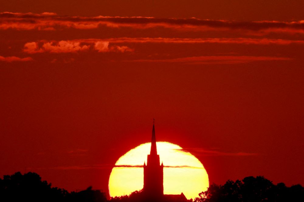 A church is pictured at sunset during a heat wave in Sancourt, France, July 12, 2023. A blistering and deadly heat wave is sweeping Europe, potentially bringing record-breaking temperatures and raising serious concerns about the impacts on people’s health, especially as the continent welcomes an influx of tourists. (OSV News/Reuters/Pascal Rossignol)