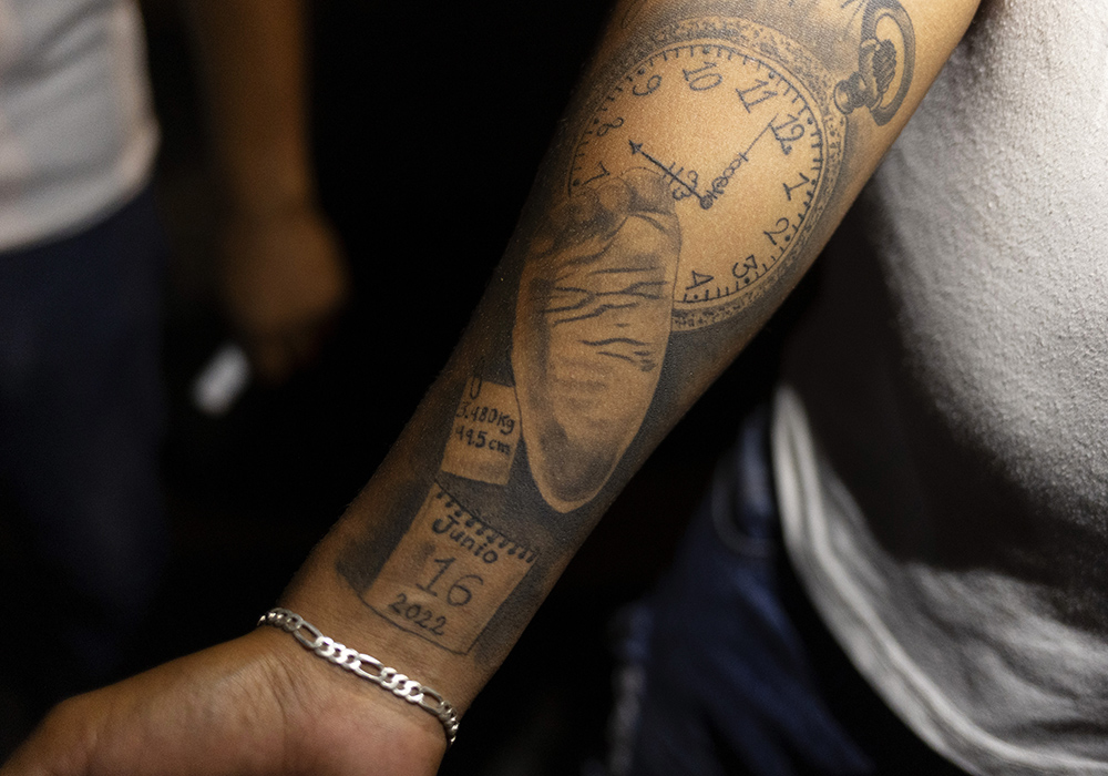 Fernando Barrientos, miembro de Los Monckis, muestra a la Hna. Sandra López García un tatuaje dedicado a su hijo Liam, durante una de sus visitas semanales al lugar de reunión de la banda juvenil en Monterrey, México.  (Foto: GSR/ Nuri Vallbona)