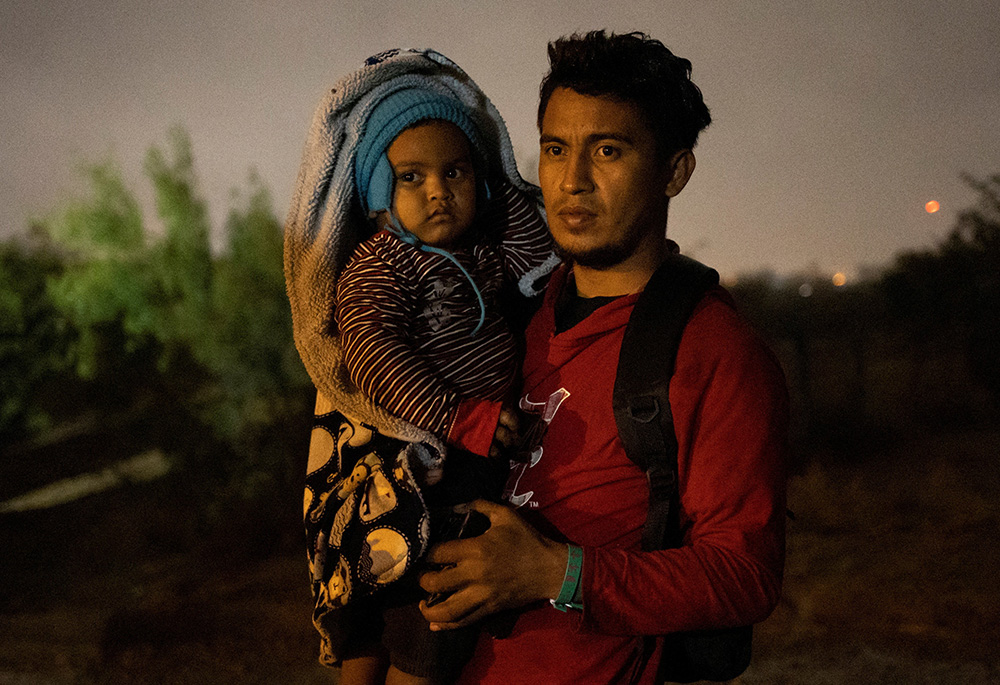 An asylum-seeking migrant from Honduras holds his 2-year-old son as he awaits to surrender to border agents after being smuggled across the Rio Grande river from Mexico into Roma, Texas, Nov. 18, 2022. (CNS/Reuters/Adrees Latif)