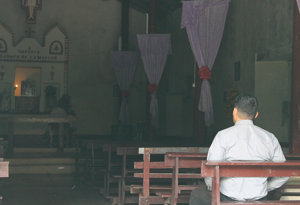 Fr. Luis Melquiades, a 33-year-old priest, sits inside St. Anthony of Padua Church in Mercedes de Oriente, Honduras. When Melquiades was 14, his father left for the U.S. and returned 16 or 17 years later.  (NCR photo/Brian Roewe)