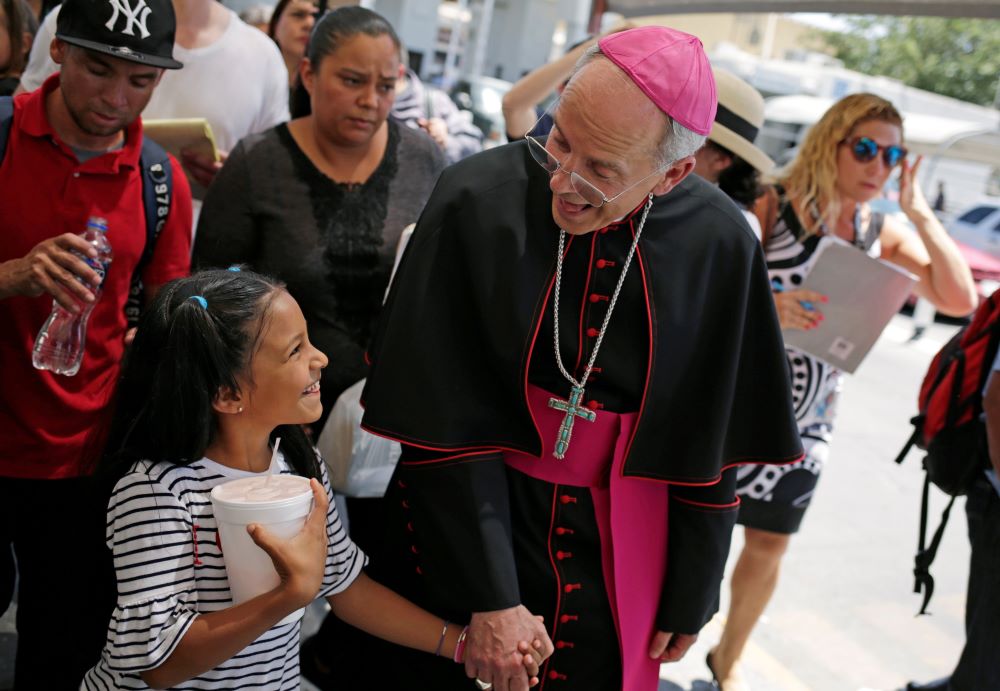 Bishop holds a little girl's hand as they walk among a group.