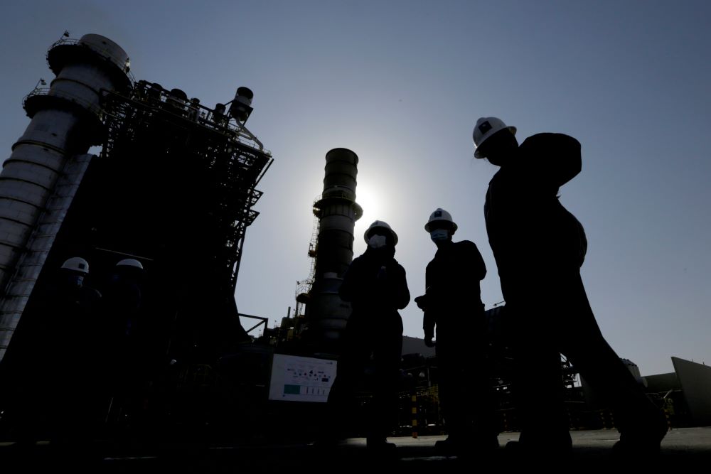 Saudi Aramco engineers walk in front of a gas turbine generator at Khurais oil field during a tour for journalists, about 93 miles east-northeast of Riyadh, Saudi Arabia on June 28, 2021.