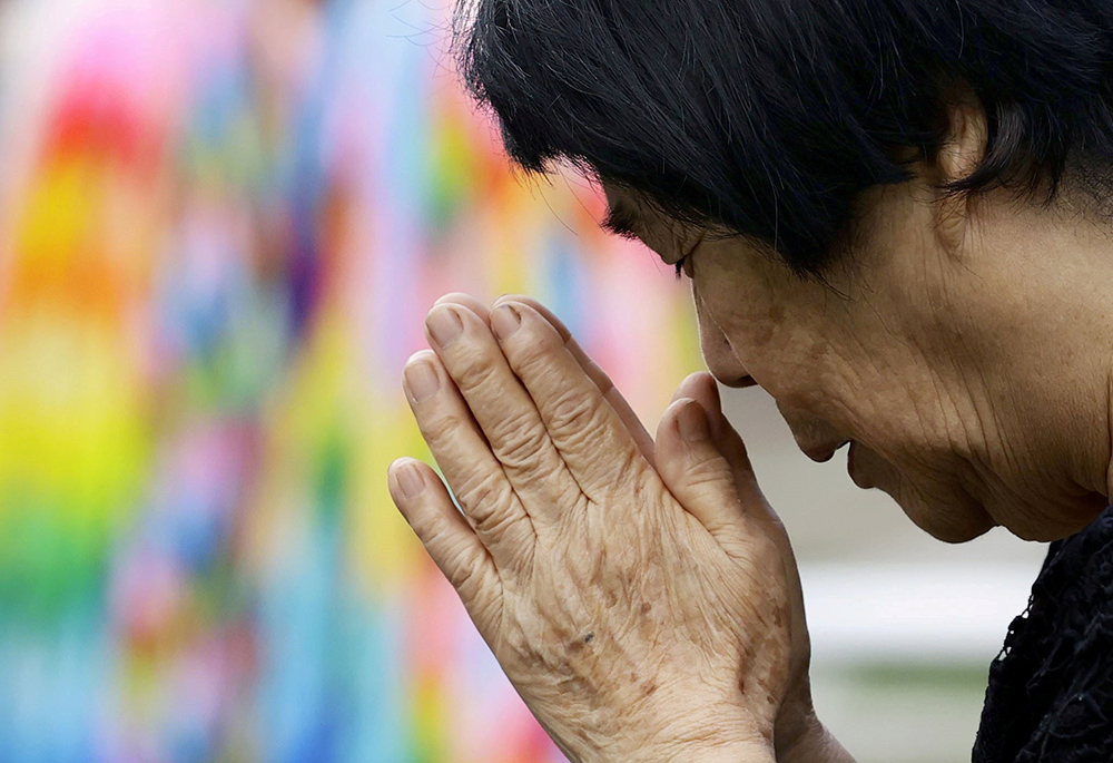 A woman prays for victims of the 1945 atomic bombing at Nagasaki's Atomic Bomb Hypocenter Park in Japan Aug. 9, 2020, the 75th anniversary of the bombing. Former priest Robert Cushing is in Japan leading a reconciliation pilgrimage for the bombings with 10 others, most of them members of Pax Christi USA. (CNS/Reuters/Kyodo)