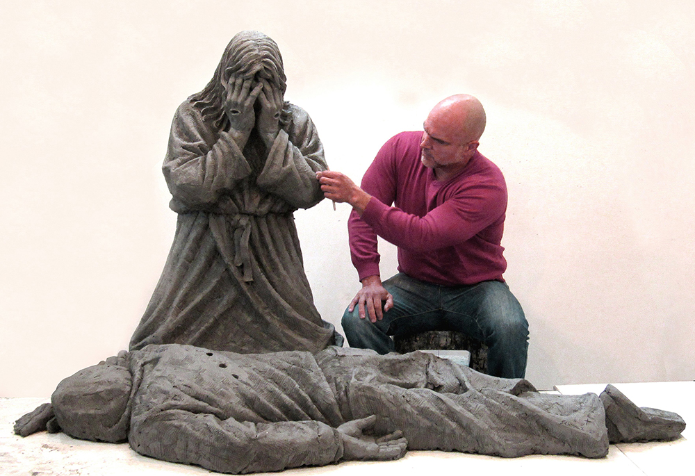 Timothy P. Schmalz is pictured in an undated photo working on his life-sized clay sculpture titled "Thou Shalt Not Kill," which depicts Jesus kneeling over a victim of gun violence. Some 60 people gathered March 25 outside of St. Sabina Catholic Church in Chicago for a first look at the sculpture, which the artist donated to the parish. (OSV News/Timothy P. Schmalz)