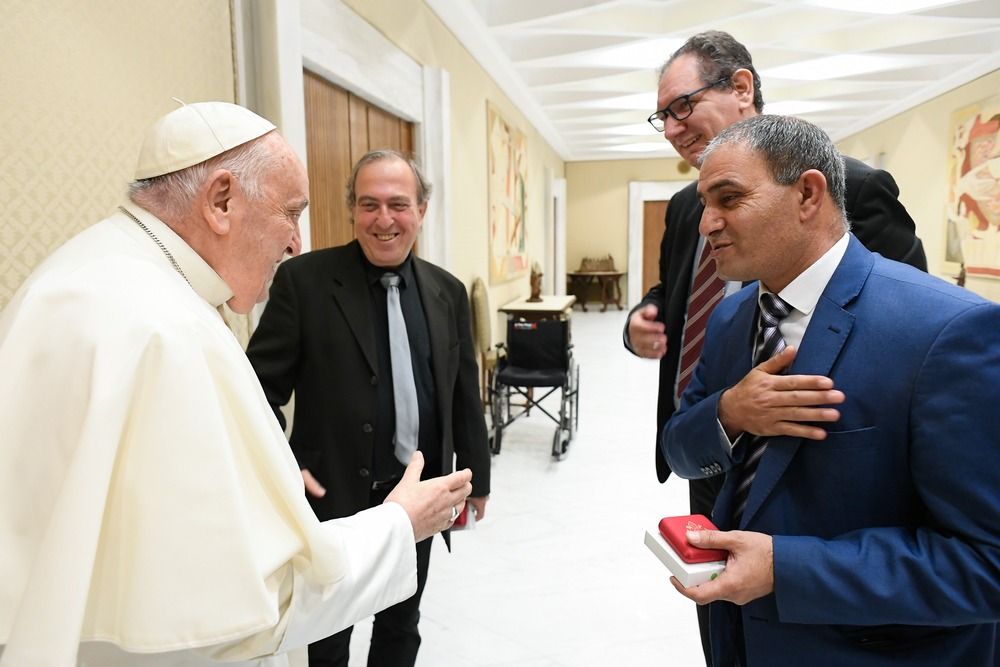 Pope Francis talks with two men. 