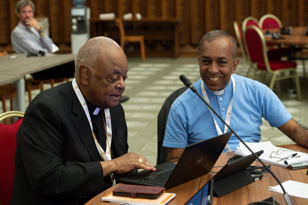 Cardinal Wilton Gregory of Washington and Redemptorist Fr. Vimal Tirimanna of Sri Lanka work during a break at the assembly of the Synod of Bishops in the Vatican's Paul VI Audience Hall Oct. 10. 