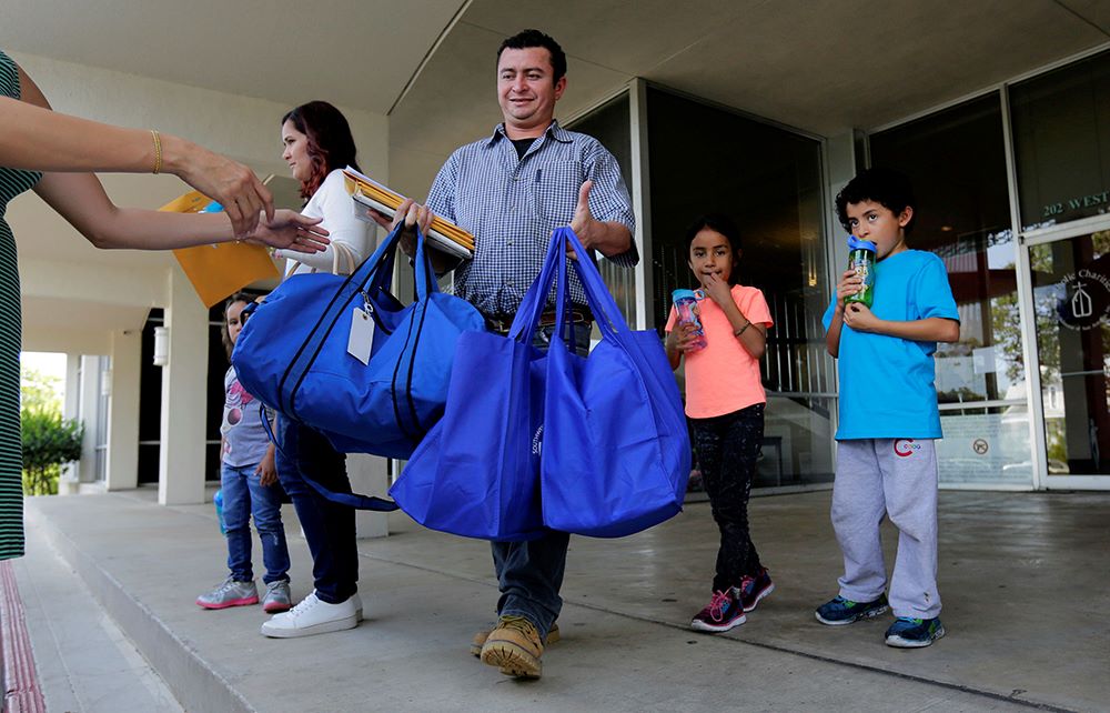 Gerarado Reconco Lara, center, and his children Maria, 6, and Gerardo, 8, leave a Catholic Charities facility July 23, 2018, in San Antonio. The family, immigrants from Honduras, was reunited the night before. (RNS/AP/Eric Gay)