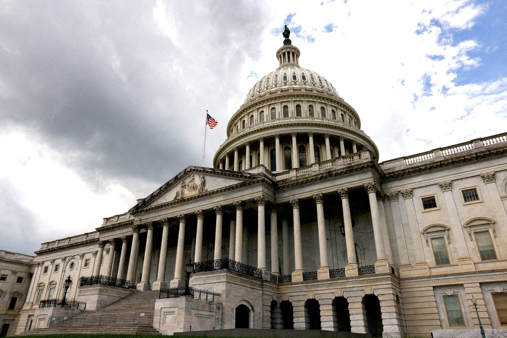 Looming edifice of U.S Capitol, darkened by overcast skies. 