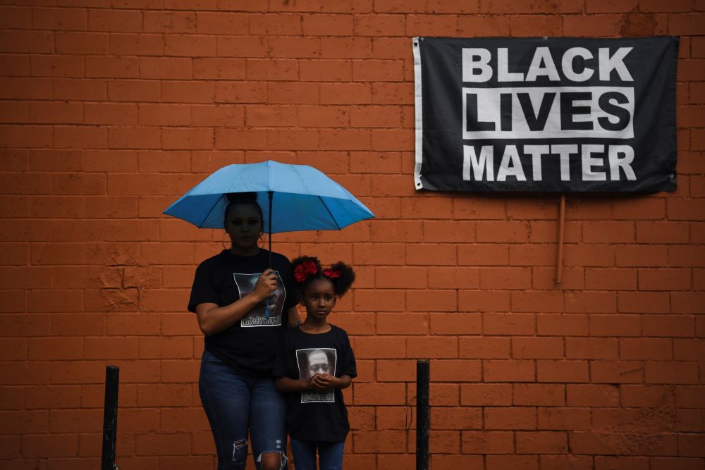 Brittany Elmore of Houston poses for a photo with her daughter Brooklyn near a "Black Lives Matter" sign May 23, 2021.
