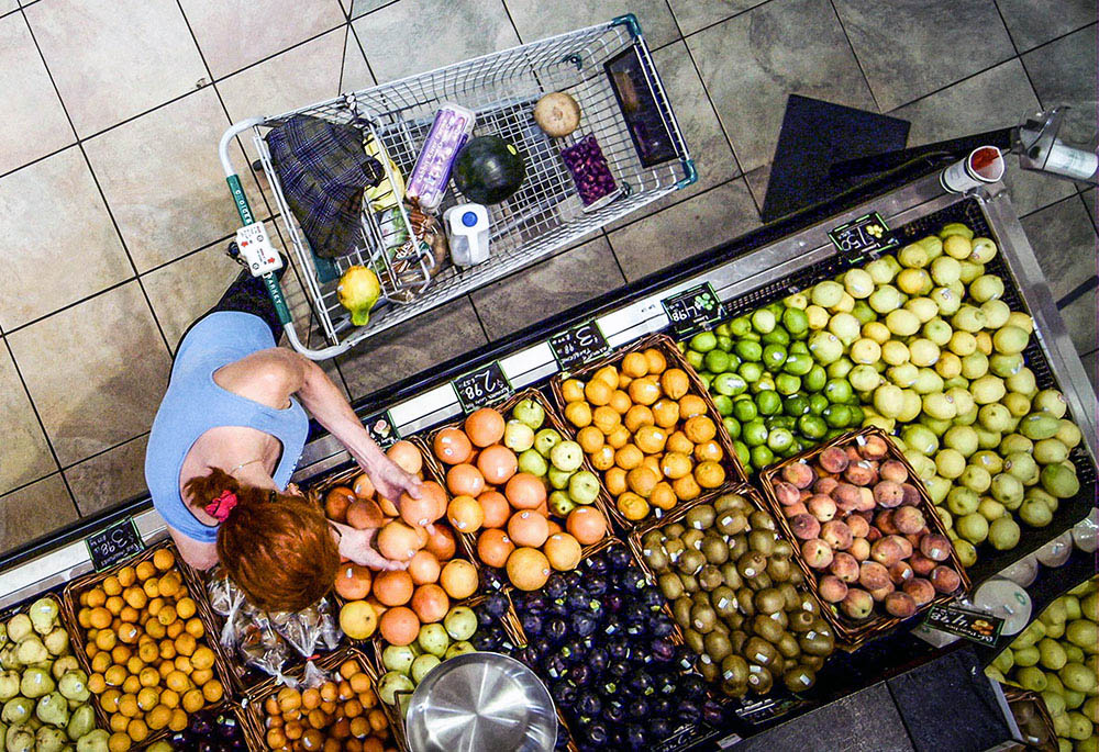A grocery shopper picks through fruit in the produce section. Most fruits and vegetables are culled due to aesthetic issues rather than safety concerns. (Courtesy of Peg Leg Films –Scene from "Just Eat It: A Food Waste Story")