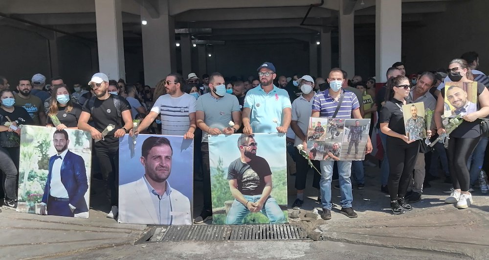 Families of the 10 firefighters who died in the Beirut port blast stand with photos of relatives at the brigade headquarters Aug. 4, one year after the tragedy. (CNS photo/Doreen Abi Raad)