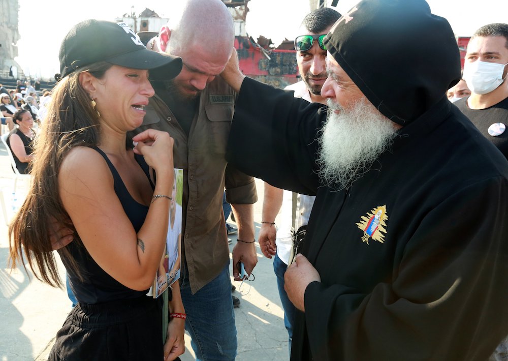 Maronite Fr. Elias Maroun Gharious comforts relatives of victims during a Mass to mark the one-year anniversary of Beirut's port blast Aug. 4. (CNS photo/Mohamed Azakir, Reuters)
