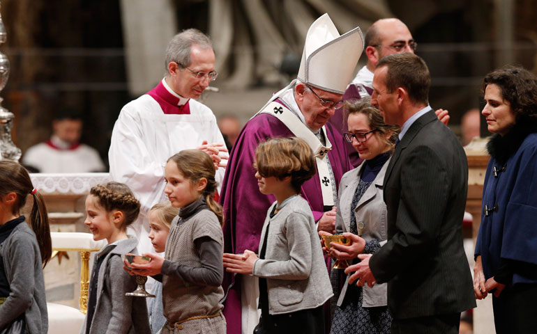 Pope Francis accepts offertory gifts from a family during Ash Wednesday Mass in St. Peter's Basilica at the Vatican Feb. 10. (CNS/Paul Haring)