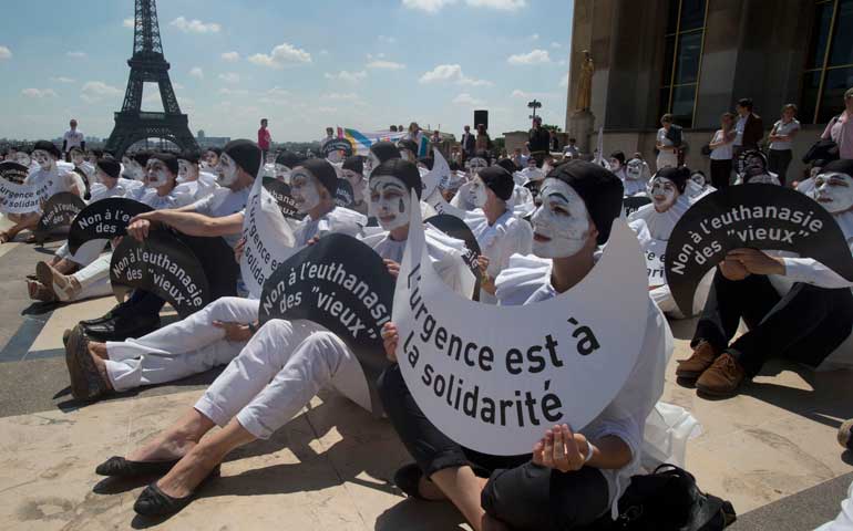 Demonstrators hold placards that read, "No to euthanasia of the elderly," and "Solidarity is urgent," in Paris June 24, 2014. (AP Photo/Michel Euler)