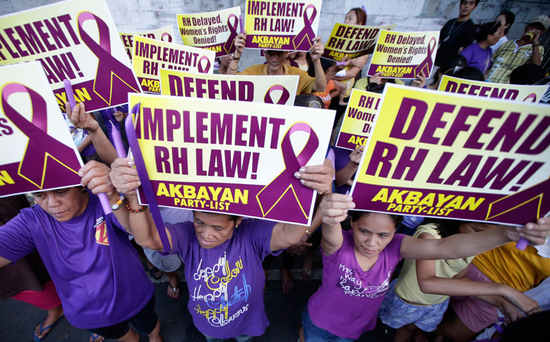 Protesters display placards during a rally March 19 at the Philippine Supreme Court in Manila to protest the court’s issuance of a 120-day status quo ante order, or a four-month delay, of the implementation of the Reproductive Health Law. (AP photo/Bullit Marquez)