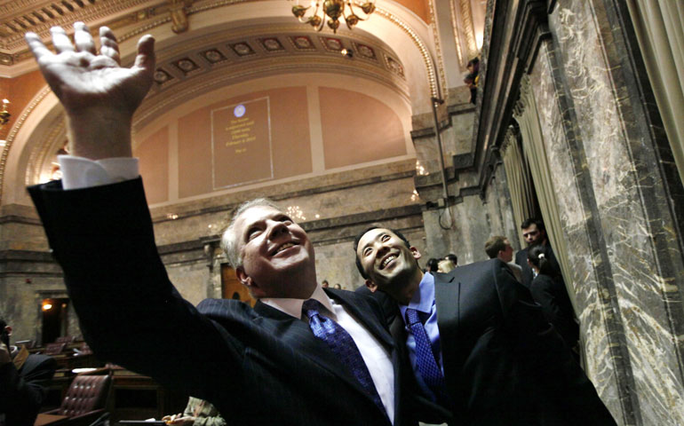Sen. Ed Murray, left, and his partner, Michael Shiosaki, wave at spectators in the upper gallery after the state Senate voted for a proposal to legalize same-sex marriage Feb. 1 in Olympia, Wash. (AP/Elaine Thompson)