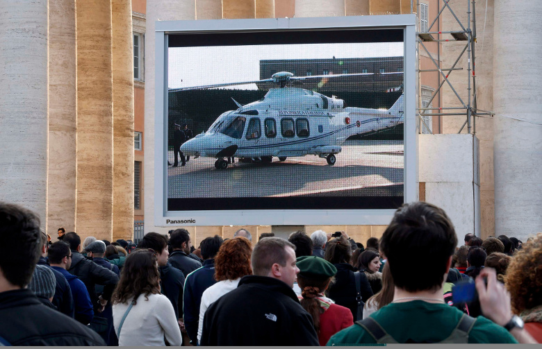 People in the Vatican's St. Peter's Square watch a giant screen showing the helicopter waiting to carry Pope Benedict XVI to the papal summer residence at Castel Gandolfo, Italy, Feb. 28, 2013 the final day of his papacy. (CNS/Reuters/Stefano Rellandini)