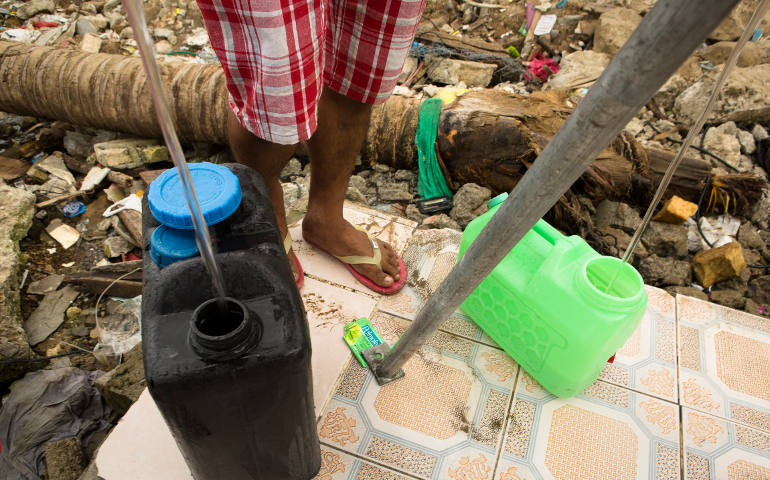A boy collects water in Anibong, a community in Tacloban, Philippines, Feb. 4. According to the Philippine government, more than 6,000 people died as a result of Typhoon Haiyan in November. (CNS photo/Tyler Orsburn)