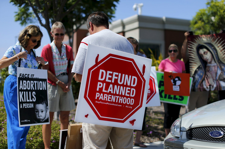 Protesters carry signs and an image of Our Lady of Guadalupe outside a Planned Parenthood clinic in Vista, Calif., Aug. 3. Boston Cardinal Sean P. O'Malley, head of the U.S. bishops' pro-life committee, urged U.S. senators to take the federal money that goes to the Planned Parenthood Federation of America and instead fund women's health care providers that do not promote abortion. (CNS photo/Mike Blake, Reuters)
