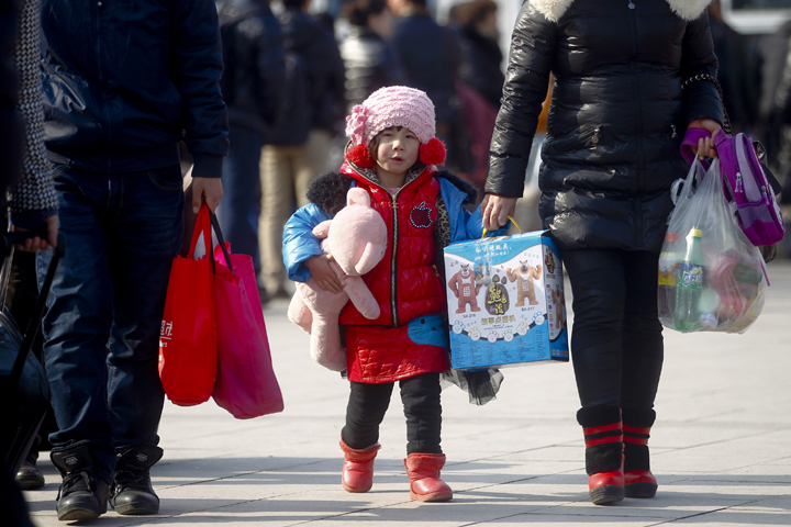 A young girl carrying a stuffed toy holds on to her mother's hand in 2013 as they walk outside the train station in Beijing. China's Communist Party leaders announced they would change the nation's one-child policy, which most strictly applied to Han Chinese living in urban areas of the country. (CNS/Diego Azubel, EPA)
