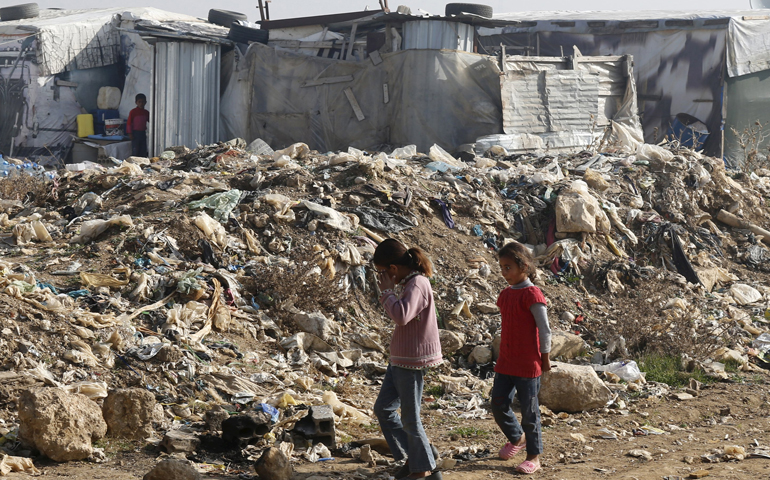 Syrian girls walk near garbage inside an informal refugee camp in Zahle, Lebanon. Lebanon continues to bear the brunt of absorbing massive numbers of refugees. (CNS/Mohamed Azakir, Reuters)