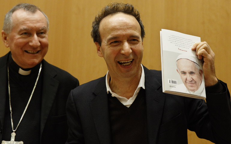 Italian actor Roberto Benigni holds a copy of the book, "The Name of God Is Mercy," during its presentation to journalists in Rome Jan. 12. At left is Cardinal Pietro Parolin. (CNS/Paul Haring) 
