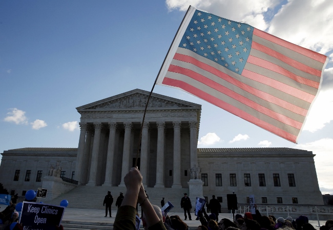 A person holds up the American flag in front of the U.S. Supreme Court in Washington March 2, the day that the court heard oral arguments in a challenge to a Texas law imposing new standards on abortion clinics and requiring abortion doctors to have hospital admitting privileges.. (CNS photo/Kevin Lamarque, Reuters) 