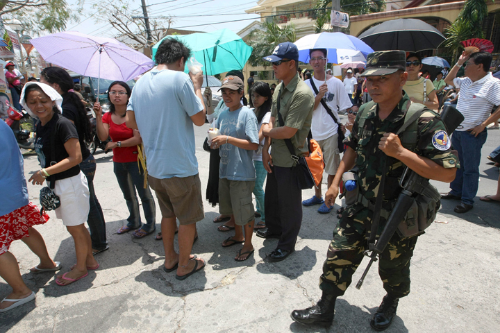 A Philippine air force trooper walks past voters lining up outside a precinct on election day in 2010 in Las Pinas. (CNS/Rolex Dela Pena, EPA)