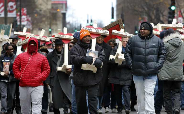 People carry crosses with names of victims of gun violence during a Dec. 31 march in downtown Chicago. Hundreds of people joined the march organized by Father Michael Pfleger, pastor of St. Sabina Parish on the city's South Side, to remember those who died by gun violence in 2016. (CNS photo/Karen Callaway, Catholic New World)