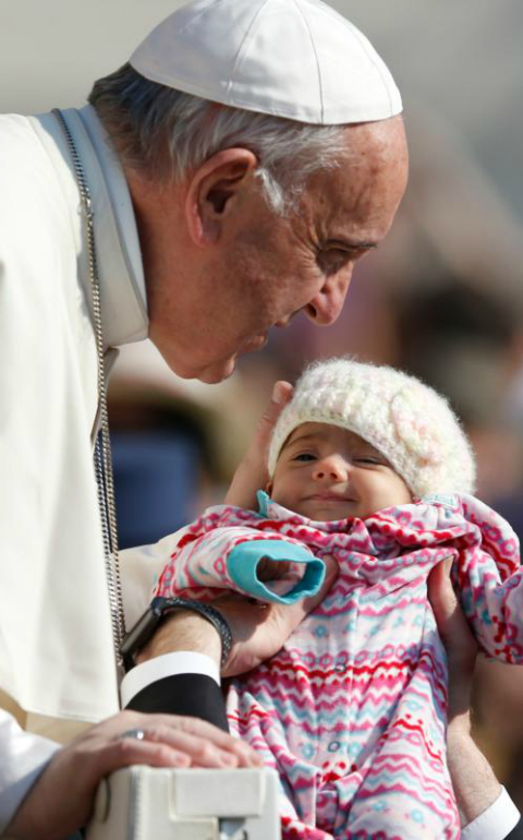 Pope Francis greets a baby during his general audience in St. Peter's Square at the Vatican April 12. (CNS photo/Paul Haring)