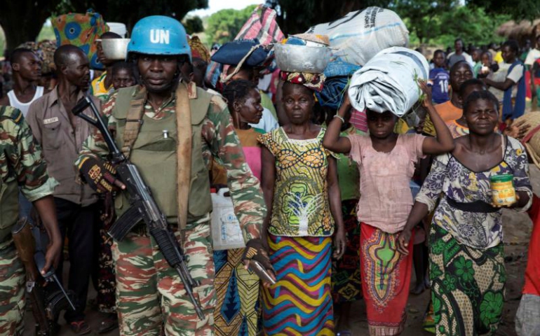 A U.N. peacekeeping soldier guards women fleeing Zike, Central African Republic, as they arrive April 26 in the village of Bambara. (CNS/Baz Ratner, Reuters)