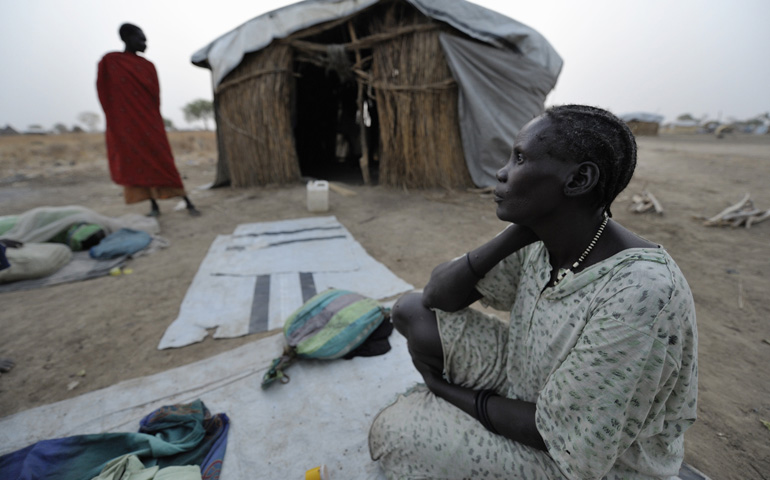 A displaced woman awakens in the morning after sleeping outside on the ground in 2013 in front of shelter in Agok, in the contested Abyei region along the Sudan-South Sudan border. (CNS/Paul Jeffrey)