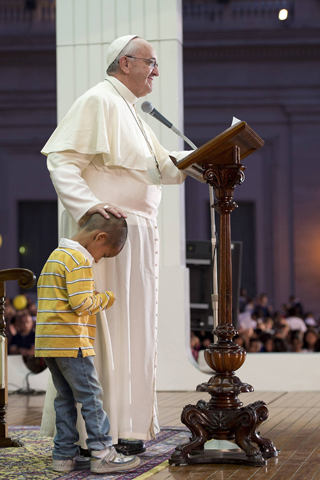 Pope Francis touches the head of a child as he addresses pilgrims Saturday in St. Peter's Square at the Vatican. He addressed an estimated 100,000 people taking part in a Year of Faith celebration of family life. (CNS/Reuters/L'Osservatore Romano)