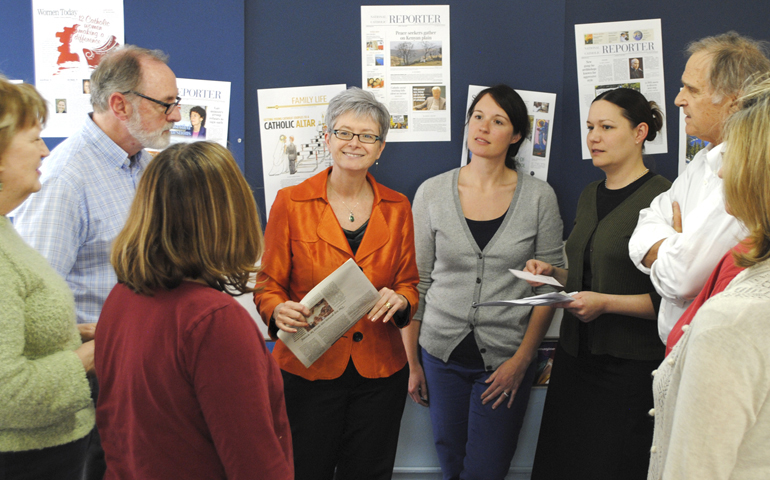 Caitlin Hendel, center, in orange, speaks with NCR and Celebration staff members. (NCR photo/Toni-Ann Ortiz)