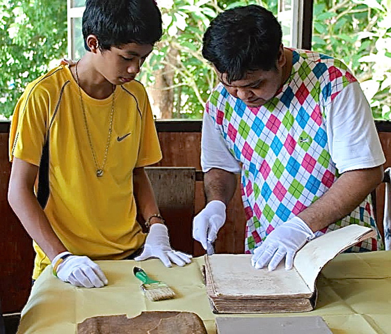 Carmelite Br. Arnulfo Alindayu, right, trains youth in handling and preserving documents at the Carmelites' San Francisco Parish, the oldest in Escalante City, Visayas Islands. (Courtesy of Carmelite Center for Social and Pastoral Communications)