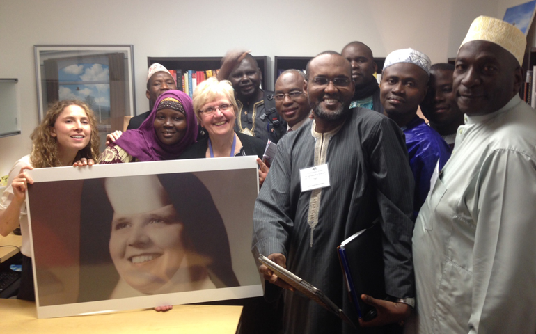 Loretto Sr. Maureen Fiedler (center), the staff of "Interfaith Voices," and African leaders pose with a photo of Fiedler as a young nun.